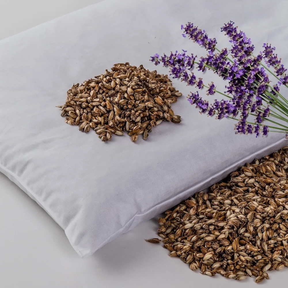 Lavender aromatherapy pillow with dried lavender seeds and fresh lavender sprigs on white fabric