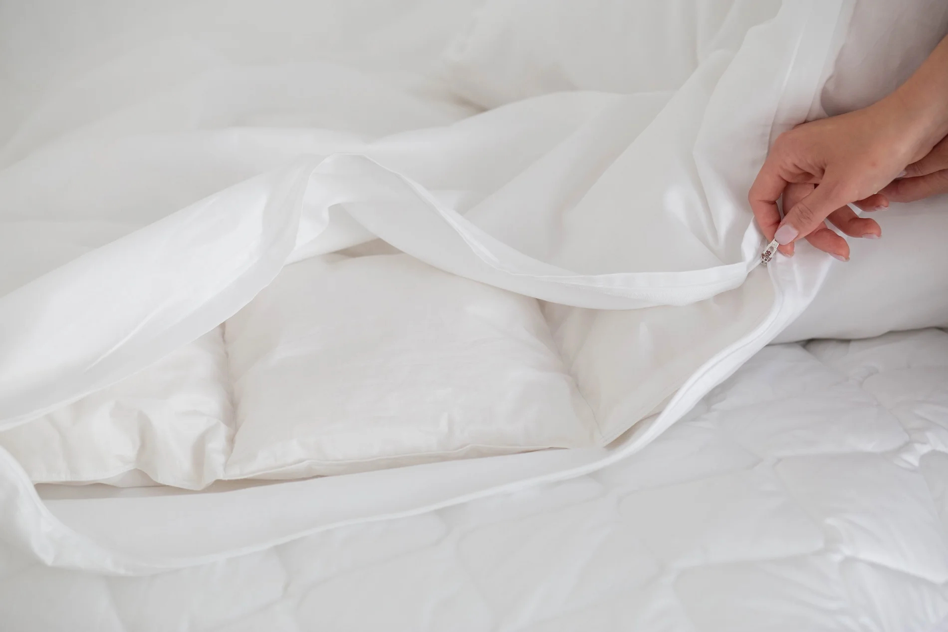 Hand demonstrating white duvet cover zipper closure showing easy-care functionality