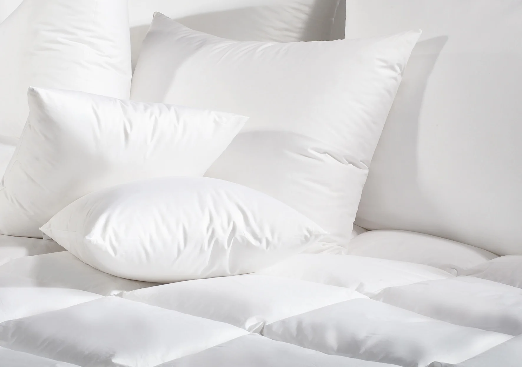 Fluffy white down pillows arranged on bed showing premium softness and comfort